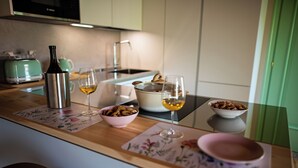 Un comptoir de cuisine avec une bouteille en acier inoxydable, deux verres à vin, un bol de noix et une casserole sur la cuisinière.