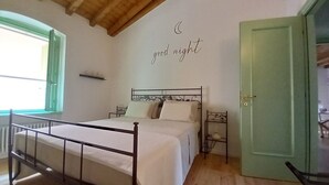 Une chambre à coucher avec un lit, un plafond en bois, une porte verte et un mur décoré d’une représentation de la lune et des étoiles.