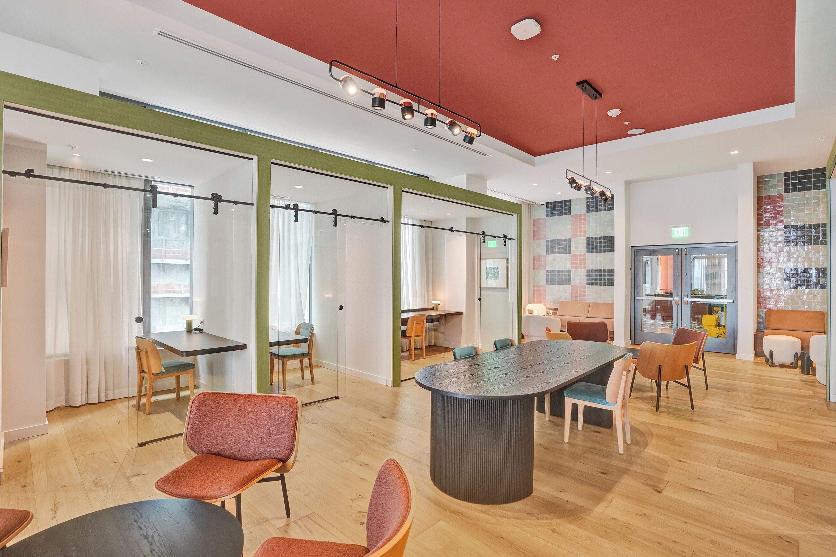 Uma sala de conferências moderna com paredes de vidro, piso de madeira e uma mesa central com cadeiras.