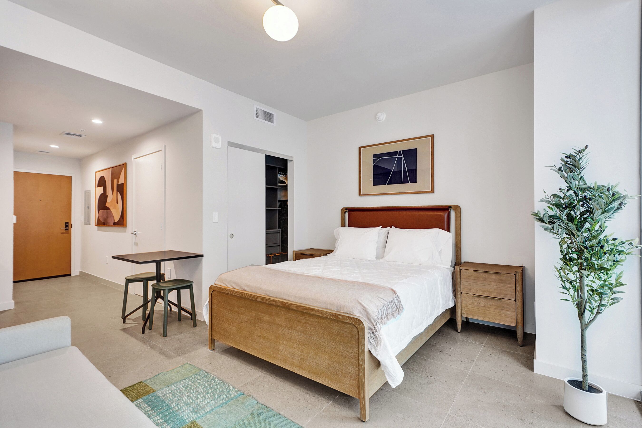 Un dormitorio con cama, mesitas de noche, escritorio y una silla.