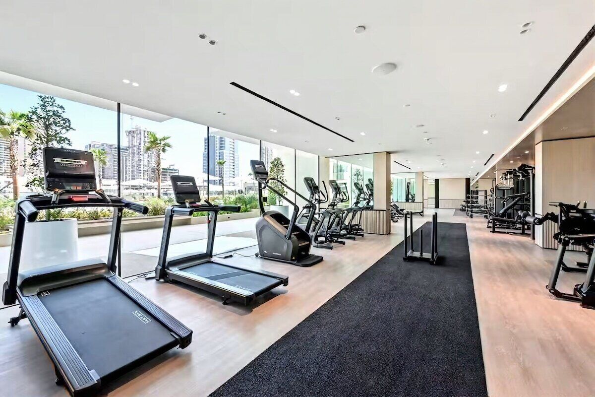 A modern gym with treadmills, elliptical machines, and weight equipment.