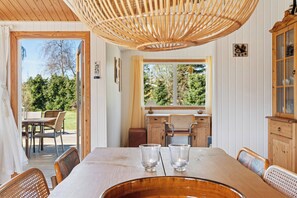 Een eetruimte met een houten tafel, stoelen en een rieten plafondlamp.