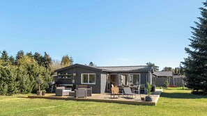 A modern house with a patio, outdoor furniture, and a large window. - Cozy holiday home near the beach (Væggerløse)