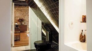 Ein modernes Badezimmer mit einer schwarzen Toilette, einem weißen Waschbecken und einer Steinwand.