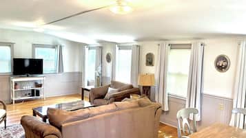 Un salon comprenant un canapé, un téléviseur et un coin repas avec une table et des chaises.