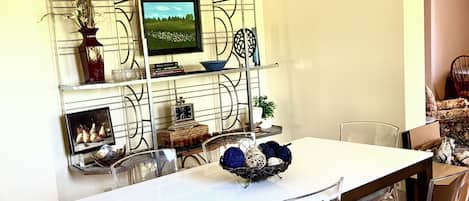 A dining area with a white table, clear chairs, a decorative wall unit, and a patterned rug.