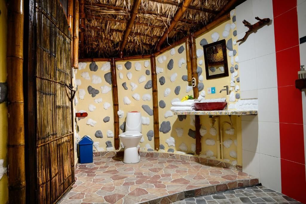 Un baño con piso de piedra, inodoro, lavamanos y zona de ducha.