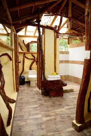 Ein rustikales Badezimmer mit Holzbalkendecke, Toilette und Waschbecken.