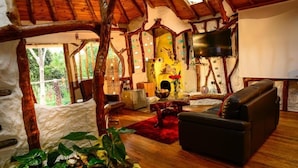 Ein rustikales Interieur mit Steinwand, Holzbalken, Kamin, Sofa und Fernseher.