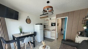 A compact living space with a kitchenette, a dining area with a table and chairs, a sofa, and a small coffee table. - Cosy seaside studio in Jard-sur-Mer - Beach 50 m away, private parking (Jard-sur-Mer)
