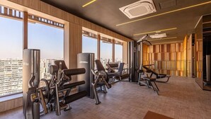 Ett modernt gym med träningsutrustning, stora fönster och utsikt över staden.