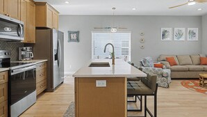 A modern kitchen with wooden cabinets, stainless steel appliances, and a central island. - Brand New Immaculate Cottage (Saint Augustine)