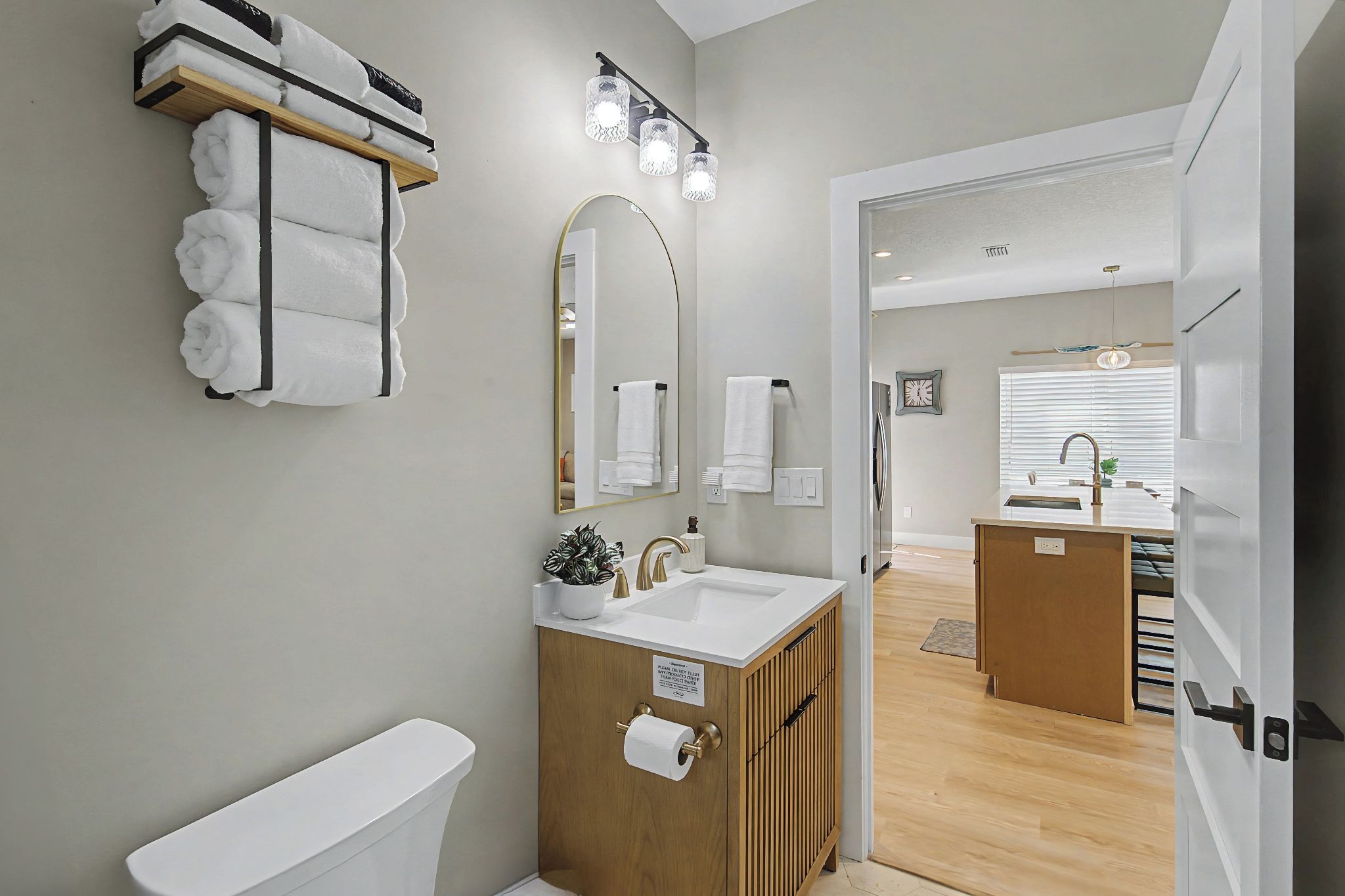 Een moderne badkamer met toilet, wastafel en spiegel. Handdoekrek met handdoeken, een houten kastje en een spiegel met verlichting.