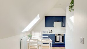Een moderne keuken met blauwe kastjes, een wit aanrecht en een dakraam.