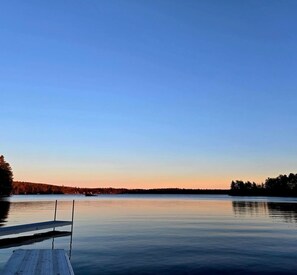 A calm lake with a wooden dock extending into the water. - Charming 1-Bedroom Cabin, full bath, outdoor sauna and boat ramp access to lake (Casco)