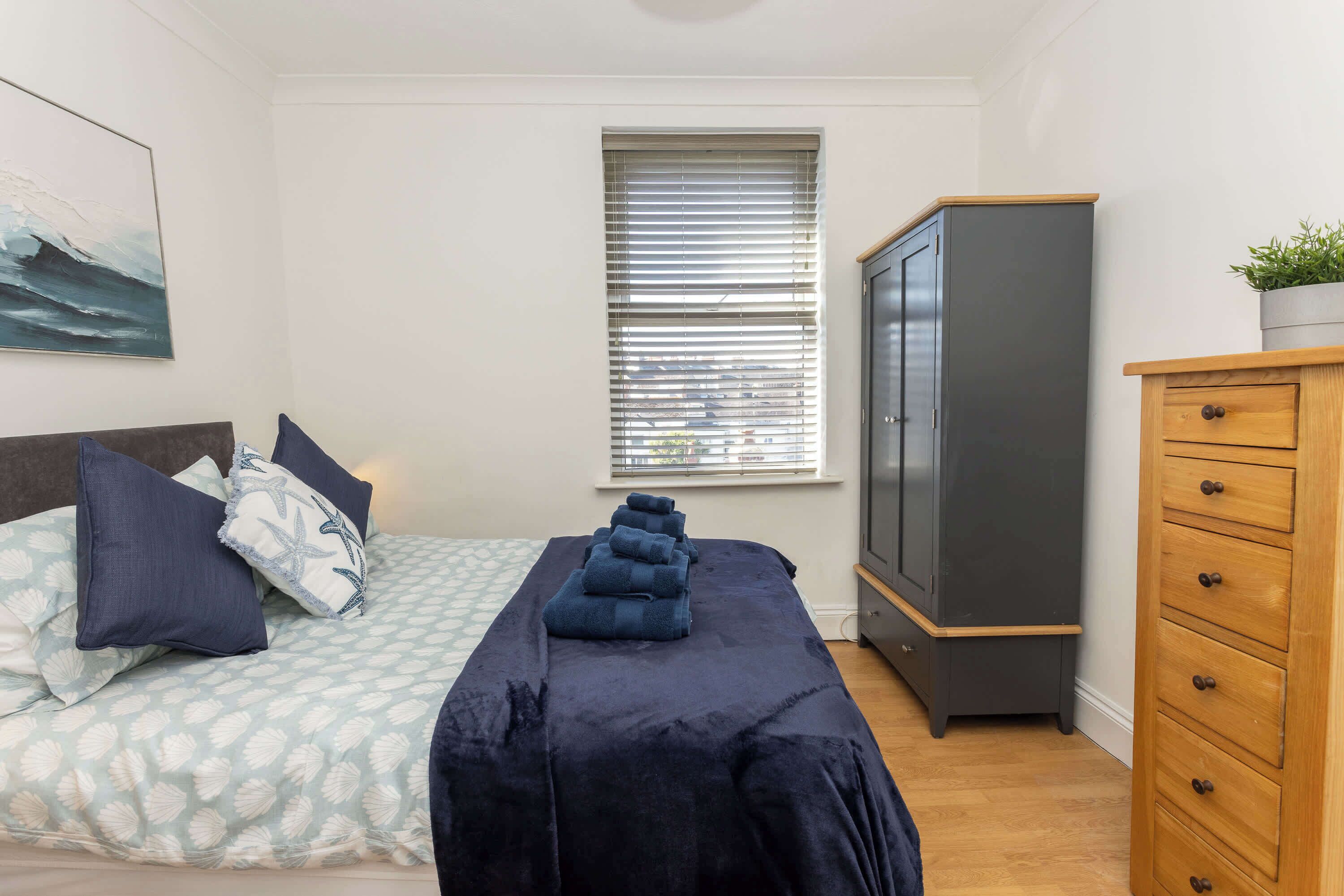 Une chambre à coucher avec un lit, une armoire et une fenêtre équipée de stores.