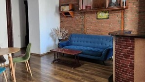 A living room with a blue sofa, wooden coffee table, and a brick accent wall. - City Guli  (Tbilisi)