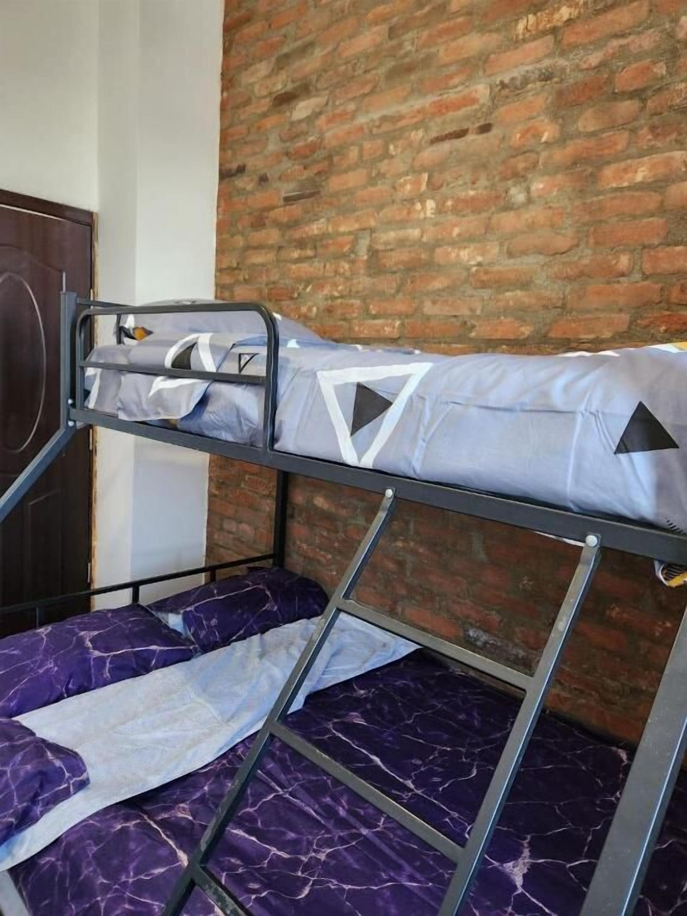 A bunk bed with a metal frame, a mattress with geometric patterns, and a purple fabric cover.