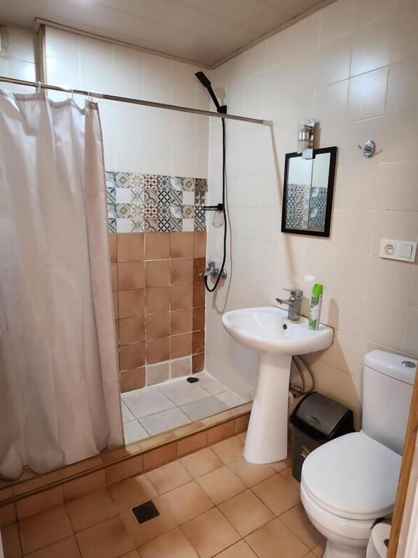 A bathroom with a shower, toilet, sink, and a mirror. - City Guli (Tbilisi)