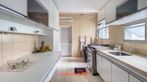 A modern kitchen with white cabinets, a stainless steel sink, and a window providing natural light. - Apartamento no Rio Proximo a Praia do Flamengo (Rio de janeiro)