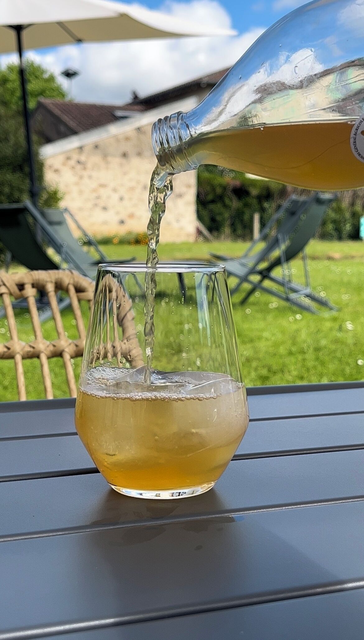 Een glas wordt buiten gevuld met een goudkleurige vloeistof.