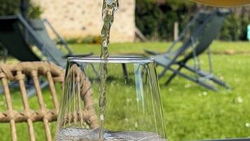 Een glas wordt buiten gevuld met een goudkleurige vloeistof.