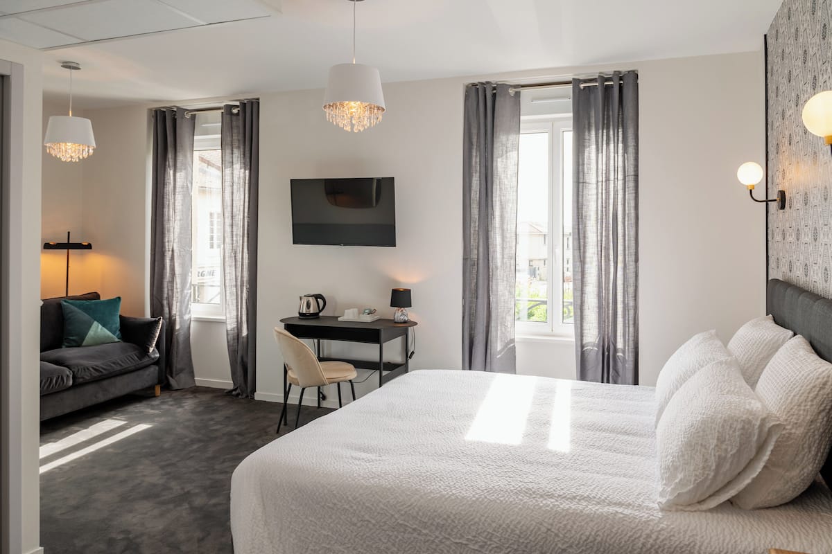 Una habitación de hotel moderna con una cama grande, un escritorio, un sofá y un televisor.