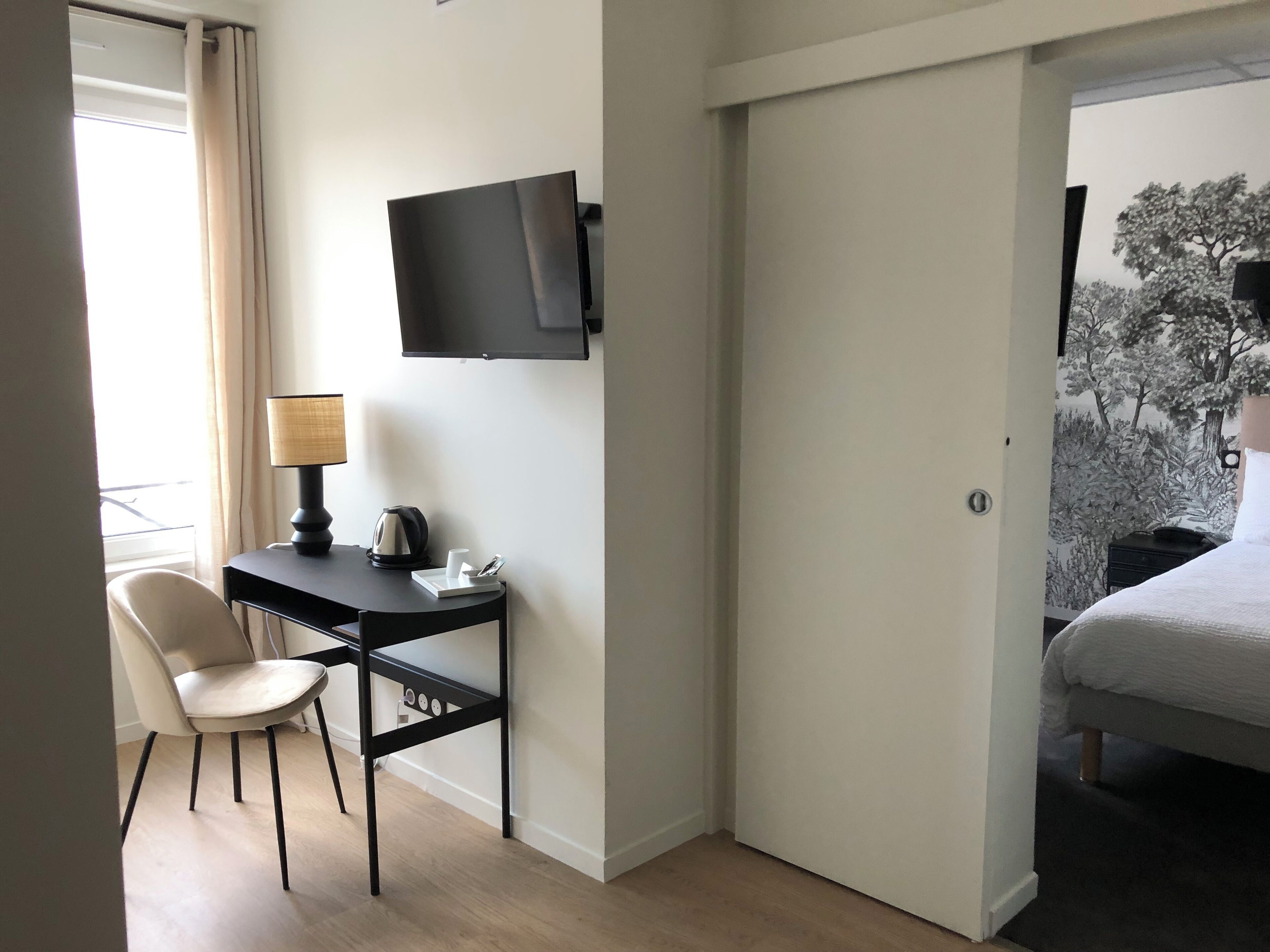 A hotel room with a desk, chair, flat-screen TV, and a bed.