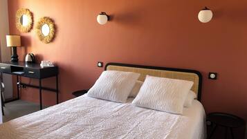 Una cama bien hecha con sábanas blancas, un escritorio con lámpara y dos luces fijadas a la pared.