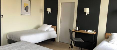 A hotel room with two beds, a desk, a chair, and a door.
