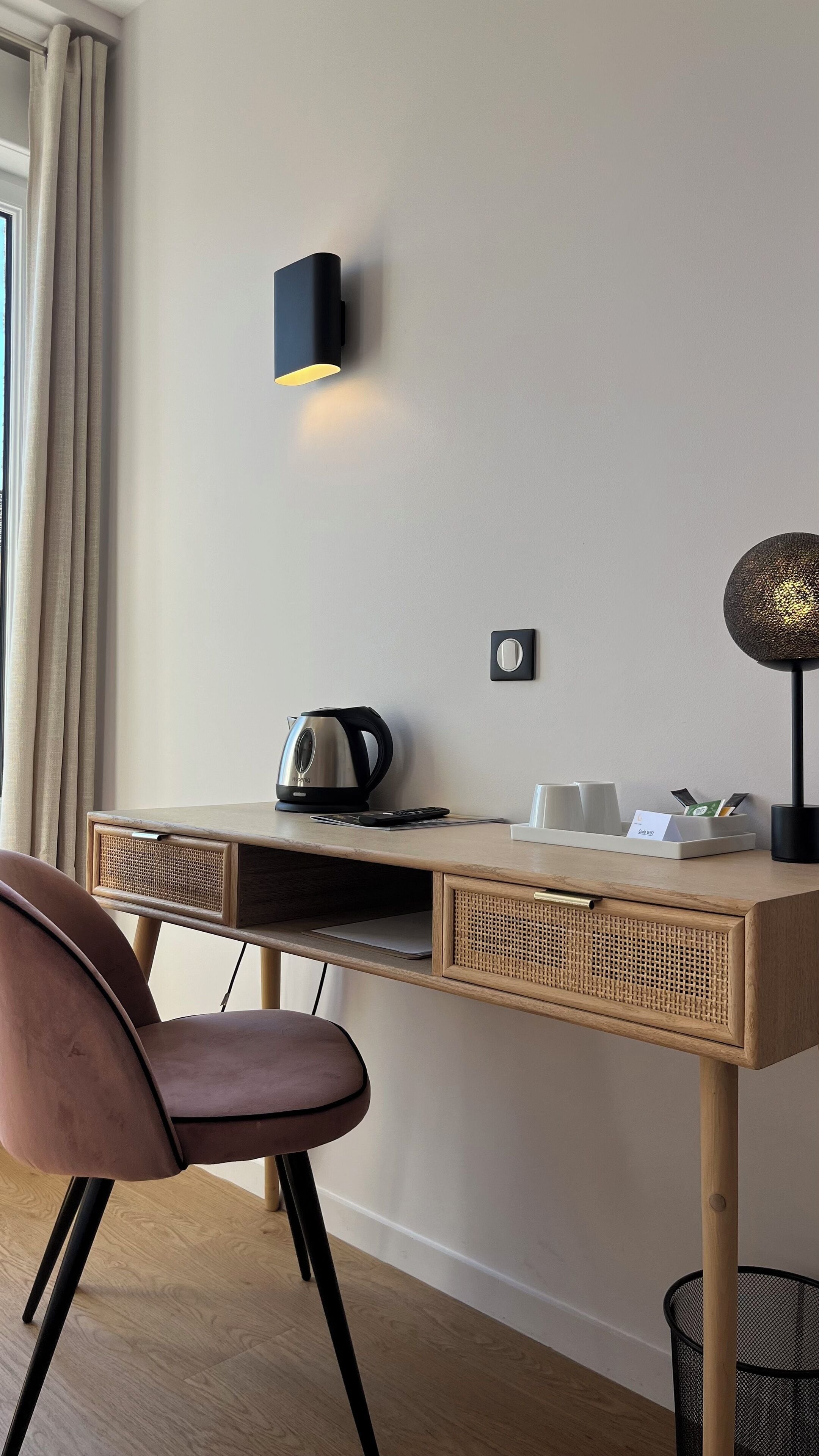 A modern desk with a kettle, a lamp, and a cup holder.