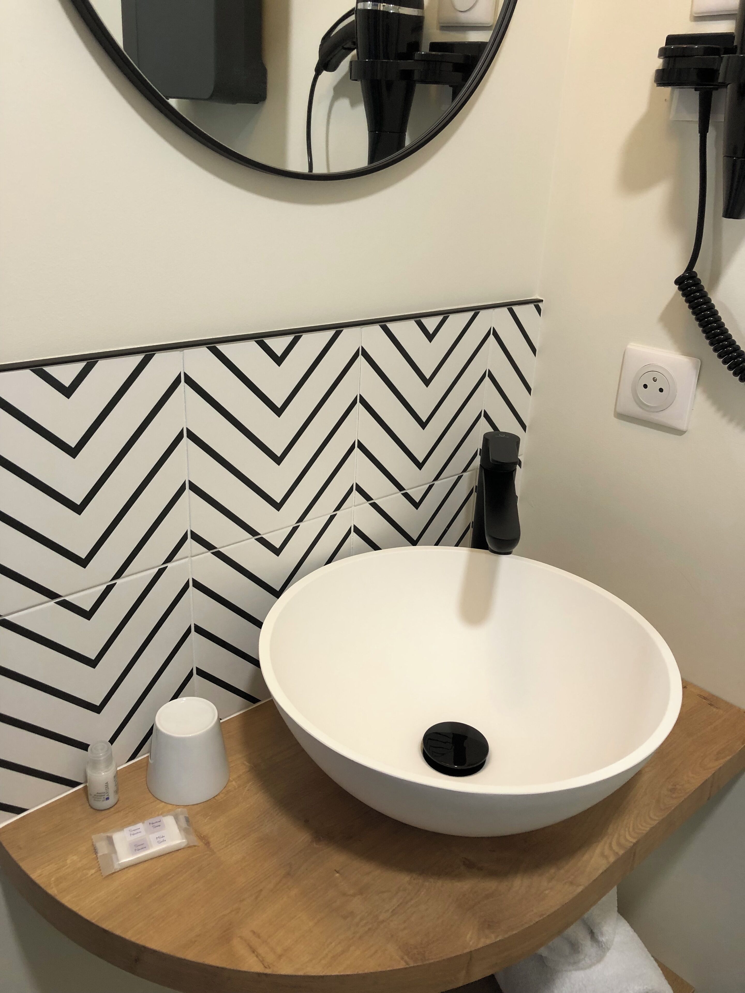 A bathroom with a white sink, a mirror, a black telephone, and a white toilet.