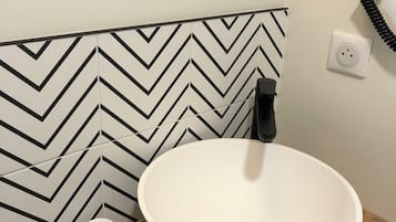 A bathroom with a white sink, a mirror, a black telephone, and a white toilet.