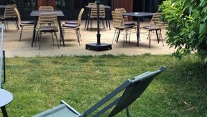 An outdoor seating area with tables and chairs, a lounge chair, and umbrellas.