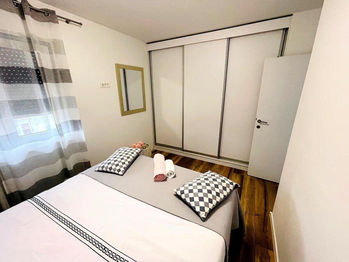 Ein Schlafzimmer mit einem Bett, zwei karierten Kissen, einem Spiegel und einem Kleiderschrank.