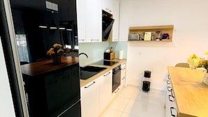 Una cocina moderna con armarios blancos, un refrigerador negro y una encimera de madera.