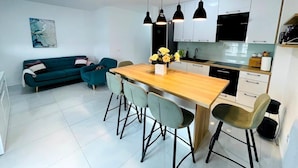 Una cocina moderna con armarios blancos, una mesa de comedor de madera y un sofá color turquesa.