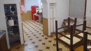 Een kamer met een geruit vloerkleed, een houten stoel, een rode koelkast en een bord waarop 'WELCOME' staat.