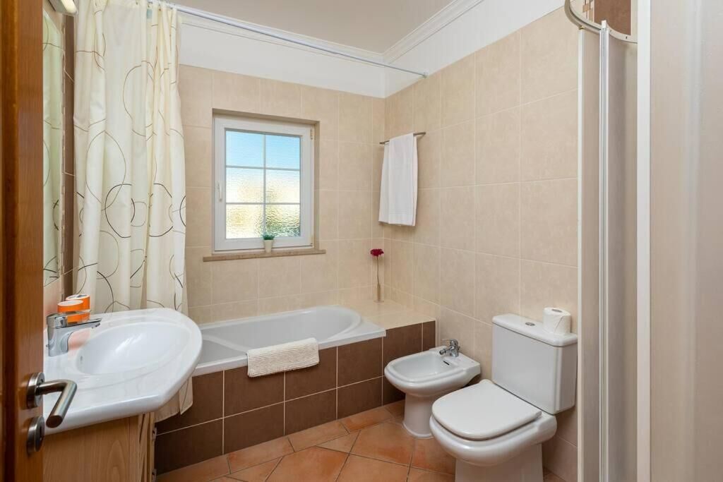 Een badkamer met een bad, wastafel, toilet en een bidet.