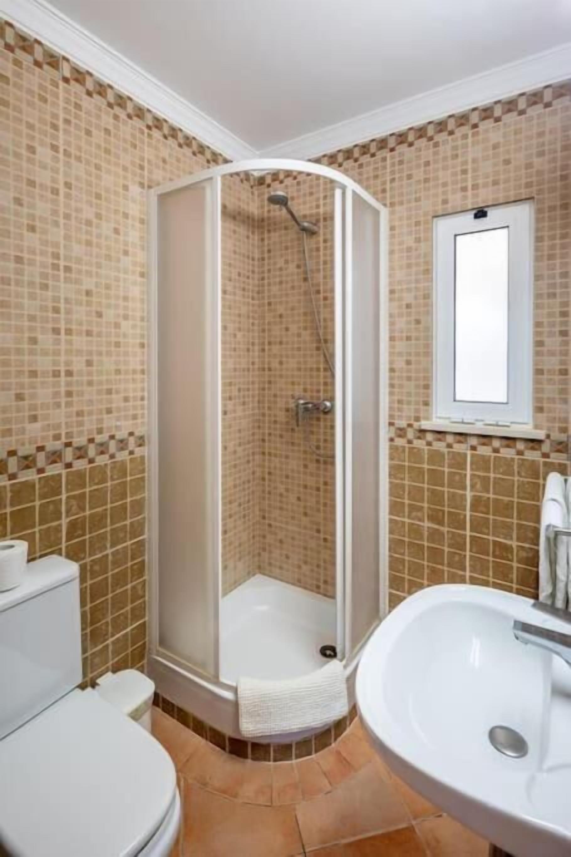 A bathroom with a shower, toilet, and sink.