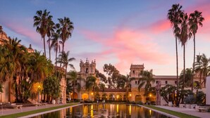 A historic building with a central courtyard and a reflective pool, surrounded by palm trees. - Pacific Beach Surf Nook Blocks to Surf & Sand (San Diego)