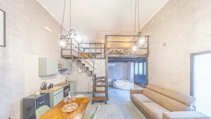 A modern interior with a kitchen, dining area, staircase, and a living room with a sofa and a bathtub.