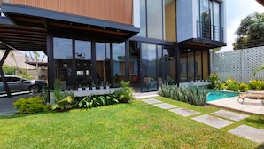 A modern house with a well-maintained lawn, a swimming pool, and a covered patio area.