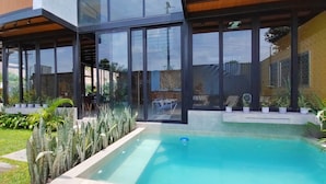 A modern house with a swimming pool, large windows, and a well-maintained garden.