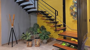 A modern staircase with wooden steps and black railings, surrounded by potted plants and decorative lanterns.