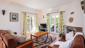 A living room with a brown sofa, a wooden coffee table, and a fireplace. - Villa Ribeiro II (Albufeira)