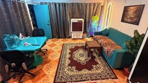 Un salon avec un canapé de couleur turquoise, un tapis à motifs, une petite table et un rideau bleu.