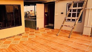 Ein Zimmer mit Holzboden, einer Leitern und einer teilweise geöffneten Tür, die in ein weiteres Zimmer führt.