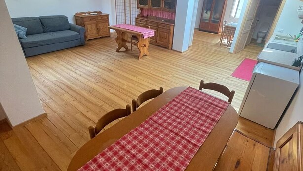 Ein geräumiges Loft mit einem Holzesstisch, einer Couch und einer Küchenzeile.