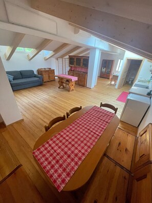 A spacious loft with a wooden dining table, a sofa, and a kitchen area. - B&B The Treehouse – Wooden Apartment (Osimo)